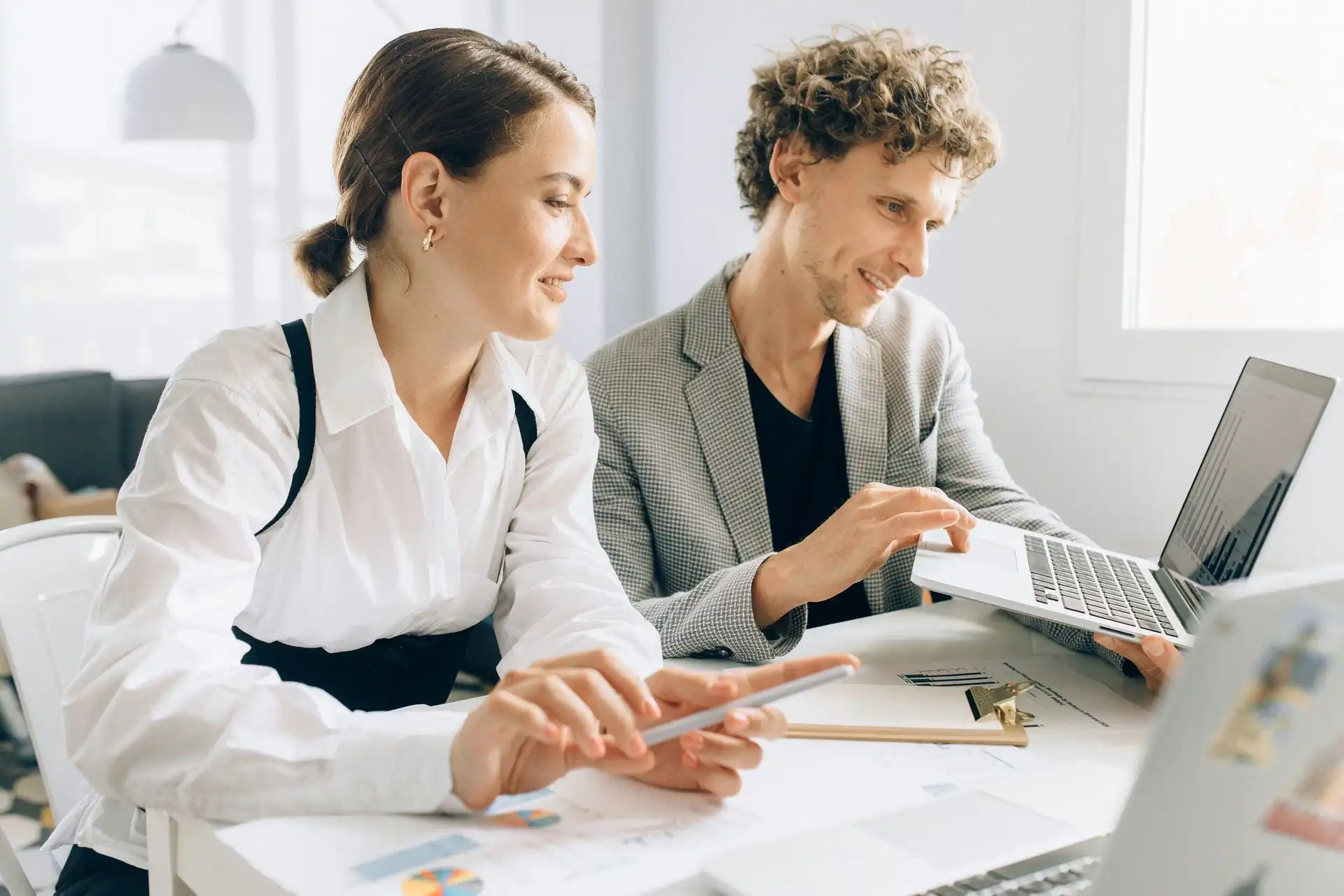 Two HR professionals collaborating over data reports on a laptop discussing HRM vs HR differences