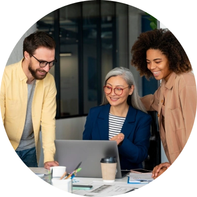 A group of diverse employees discussing ideas around a laptop in an open office environment