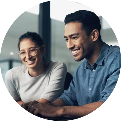 Two colleagues happily discussing weekly shift schedules and rota plans on a laptop